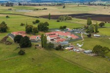 A cluster of buildings and fencing in a green countryside seen from the air.